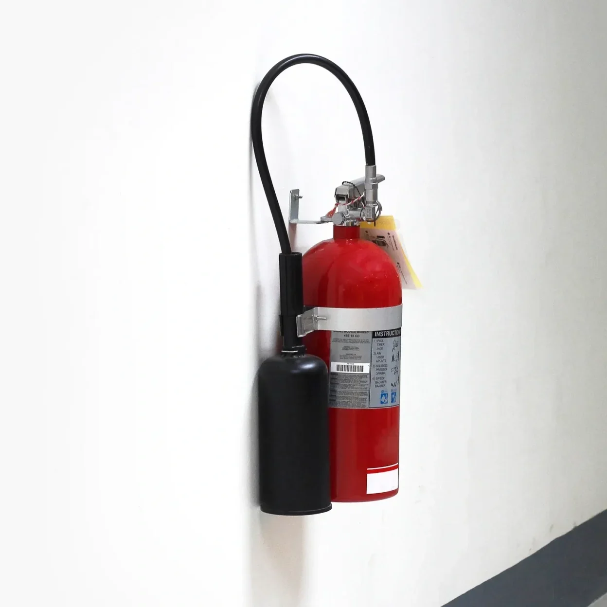 Red fire extinguisher mounted on white wall