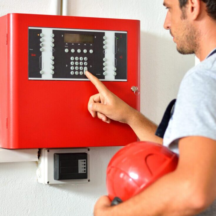 Technician operating red fire alarm control panel